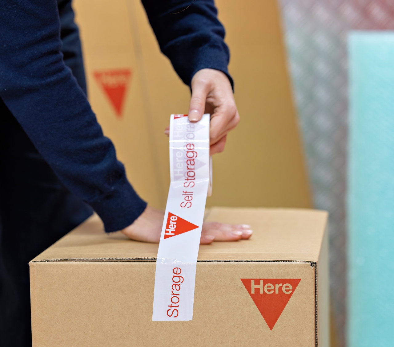 Man taping up a HERE moving box using HERE packaging tape